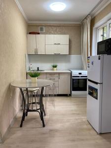 a kitchen with a table and a white refrigerator at Аппартаменты 2 / х комнатная in Ustʼ-Kamenogorsk
