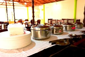 uma mesa com várias panelas e frigideiras e um bolo em CoffeeINN Homestay - Private Cottages, Jeep Ride, Home Food em Sakleshpur