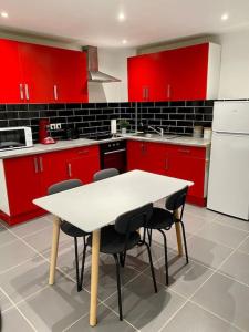 une cuisine avec des placards rouges, une table blanche et des chaises dans l'établissement Joli duplex neuf centre Seclin., à Seclin