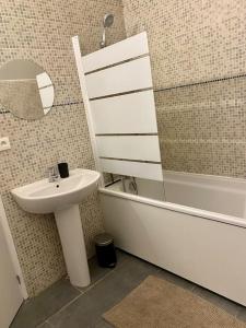 La salle de bains est pourvue d'un lavabo et d'une baignoire. dans l'établissement Joli duplex neuf centre Seclin., à Seclin