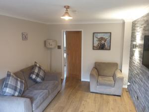 ein Wohnzimmer mit einem Sofa und 2 Stühlen in der Unterkunft Oldwood Place Townhouse in Livingston