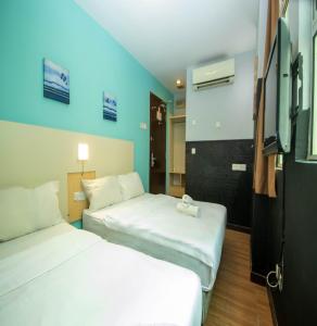 a hotel room with two beds and a tv at JQ Station Eight Inn in Ipoh
