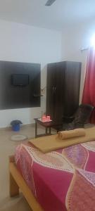 a bedroom with a bed and a tv and a table at Hotel Khushi Waves in Arpora