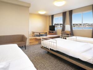 ein Hotelzimmer mit 2 Betten und einem TV in der Unterkunft KAMENOI HOTEL Oarai in Oarai