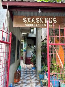 una señal en la puerta de una tienda con macetas en Seaslugs Traveller's Inn, en El Nido