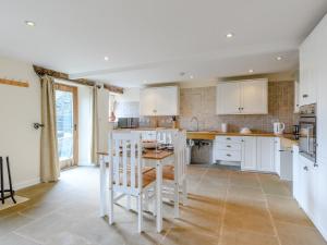 1 Bed in Hathersage 78016 في Bradwell: مطبخ مع دواليب بيضاء وطاولة وكراسي