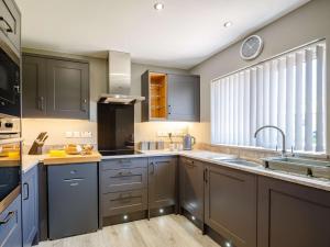 una cocina con armarios grises y fregadero en 3 Bed in Fairbourne 86841, en Fairbourne