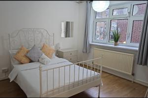 a white bed in a room with windows at London E1 Rooms in London