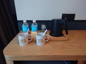 three coffee mugs sitting on a table with water bottles at Katel Kuala Lumpur formally known as K Hotel in Kuala Lumpur