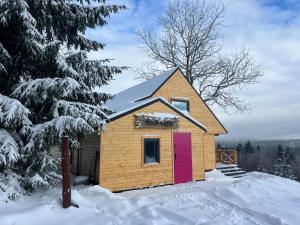 a cabin with a red door in the snow at Nasza Chata in Duszniki Zdrój