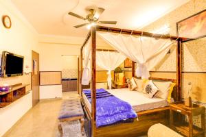 House Of Comfort Greater Noida في نويدا الكبرى: غرفة نوم مع سرير مظلة مع مروحة سقف