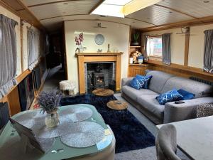 sala de estar con sofá y chimenea en Luxury boat - The Thistle Dream, en Uxbridge