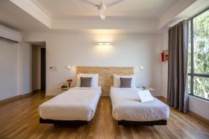 Habitación con 2 camas, suelo de madera y ventanas. en Townhouse 013 New Friends Colony, en Nueva Delhi