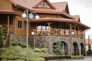 Cette grande maison en bois dispose d'une terrasse couverte et d'un éclairage de rue. dans l'établissement Na Pagorbi Lutsk, à Loutsk