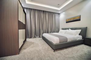 een slaapkamer met een bed en een groot raam bij فندق قمم بارك Qimam Park Hotel 7 in Al Baha