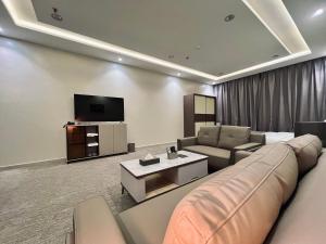 a living room with a couch and a tv at قمم بارك الباحة Qimam Park Hotel 7 in Al Baha