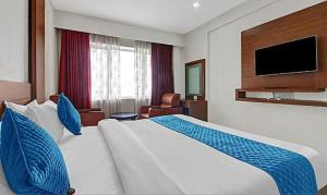 a hotel room with a large bed and a television at FabHotel Majestic South Gate in Trivandrum