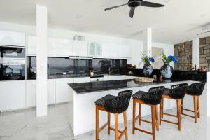 una cucina con armadietti bianchi e sgabelli da bar di Luxury Blue Coco Sea View Villa - 4x4 SUV included a Ko Samui