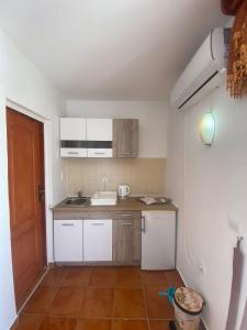 a small kitchen with white cabinets and a sink at Apartments Mitrović Podličak in Sveti Stefan