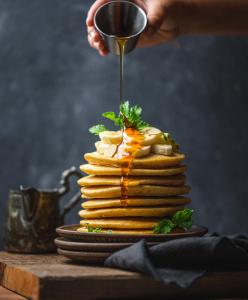 a stack of pancakes with syrup being poured on top at Hotel Claytone Near Delhi Airport in New Delhi