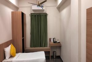 a room with a bed and a green shower curtain at Signum Cityscapes Landmark in Dahej