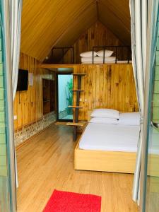ein Schlafzimmer mit einem Bett in einem Holzhaus in der Unterkunft Homestay Suối Khoáng Minh Hằng in Yên Bái