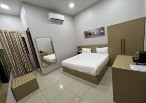 um pequeno quarto com uma cama e um espelho em Ixoras Hotel Victoire em Kinshasa