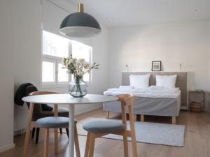 a white bedroom with a bed and a table and chairs at Bob W Koti Ullanlinna in Helsinki