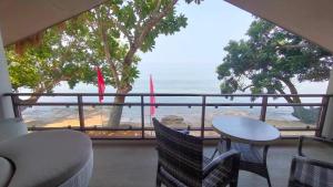 balcón con mesa, sillas y vistas al océano en Alam Indah Busuanga Beach and Villas, en Busuanga