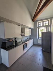 Superbe appartement duplex en hyper centre في لو بوي: مطبخ مع دواليب بيضاء وثلاجة