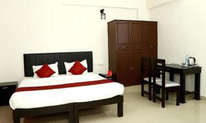 FabExpress Majestic Le Frank في Kazhakuttam: غرفة نوم مع سرير مع وسائد حمراء ومكتب