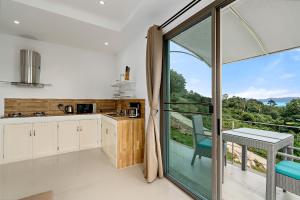 a kitchen with a sliding glass door leading to a balcony at Villa 7 chambres vue mer in Ban Khlong Mae Nam