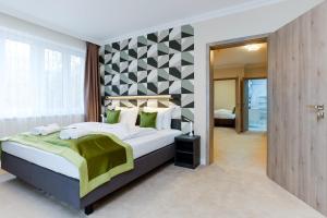 a bedroom with a large bed with green and white pillows at Lumen Gasztropanzió in Eger