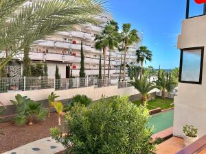 an apartment building with palm trees and a courtyard at Olympia Palmalicious Apartment in Playa de las Americas