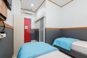 1 dormitorio con 2 camas y puerta roja en Ian Hotel Jaksa Mitra RedDoorz en Yakarta