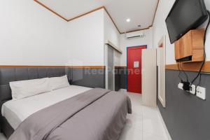 una camera da letto con un letto e una TV a schermo piatto di Ian Hotel Jaksa Mitra RedDoorz a Giacarta