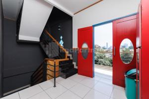 una puerta roja en una habitación con escalera en Ian Hotel Jaksa Mitra RedDoorz en Yakarta
