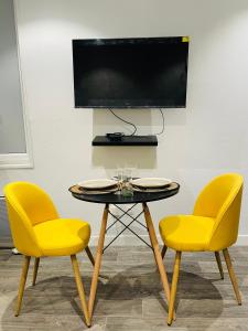 two yellow chairs and a table with a tv on a wall at Studio cosy 