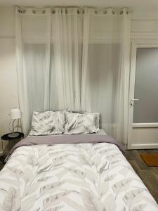 a bedroom with a large white bed with curtains at Studio cosy 