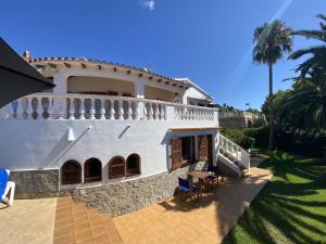 a large white house with a patio and palm trees at Villa GALERA in Son Bou