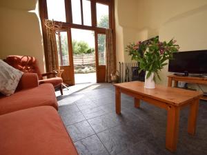 ein Wohnzimmer mit einem Sofa und einem Tisch mit Blumen in der Unterkunft 3 Bed in Ilfracombe GRAIC in West Down