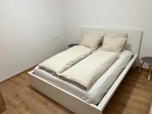un letto bianco con lenzuola e cuscini bianchi di Mountain Chalet a Fieberbrunn