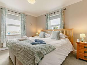 a bedroom with a large bed and two windows at 3 Bed in Newquay TREOC in Mawgan Porth
