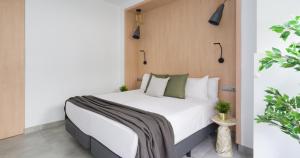 1 dormitorio con 1 cama con sábanas blancas y almohadas verdes en Tusity One, en Las Palmas de Gran Canaria