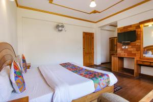 a hotel room with a bed and a television at FabHotel Prini Inn in Manāli