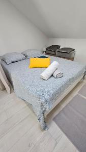 - un lit avec un oreiller jaune et des serviettes dans l'établissement La Grande Ourse - Wifi - Terrasse - Vulcania, à Saint-Ours