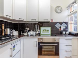 a kitchen with white cabinets and a clock on the wall at 1 Bed in Torquay 36488 in Torquay