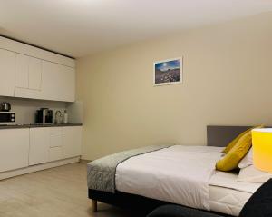 a bedroom with a bed with yellow pillows and a kitchen at Apartamenty Czarna Góra Veraneo in Sienna