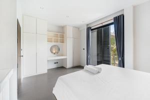 a white bedroom with a white bed and a window at Ana's House in Nathon Bay