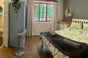 a bedroom with a bed and a dresser and a window at The Croft cottage in Knysna
